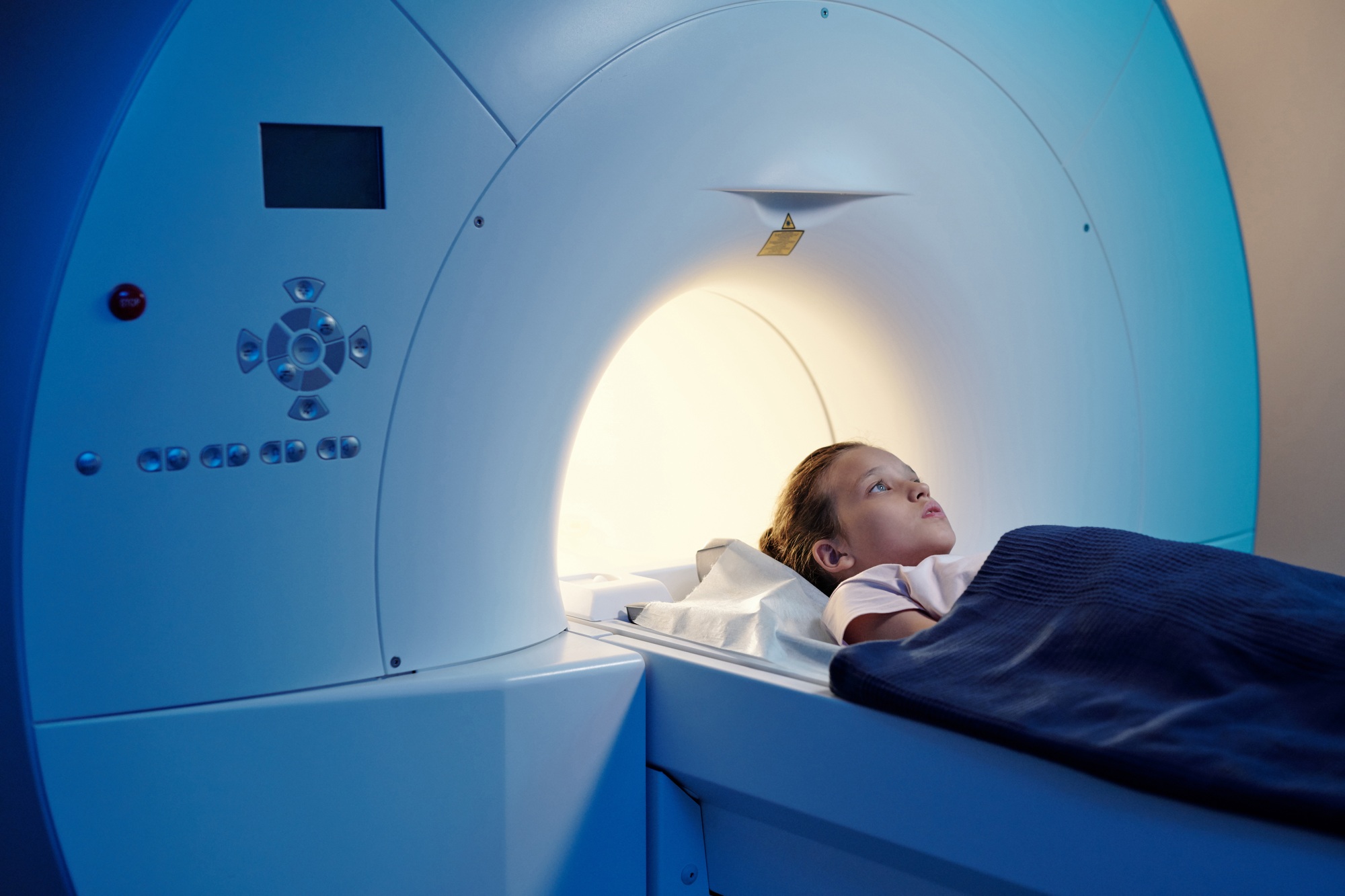 Little patient under blue towel lying on long table of mri scan machine